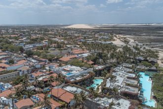 Vista aérea de Jericoacoara, com dunas, coqueiros e áreas de água próximas à vila.