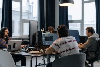 Equipe de desenvolvedores trabalha em computadores em um escritório de tecnologia.