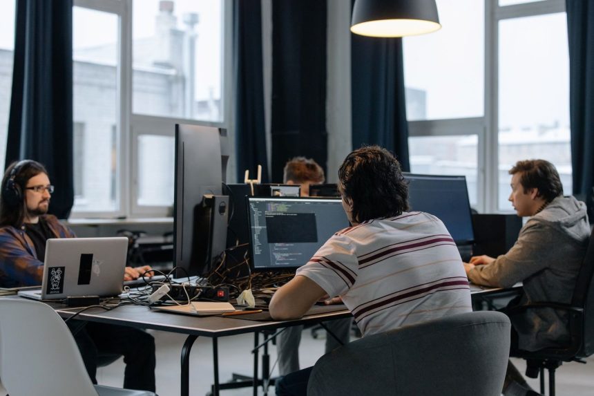 Equipe de desenvolvedores trabalha em computadores em um escritório de tecnologia.