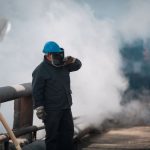 Trabalhadores industriais usando equipamentos de proteção em um ambiente com fumaça.