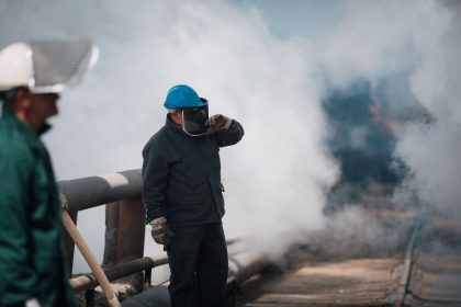 Trabalhadores industriais usando equipamentos de proteção em um ambiente com fumaça.