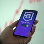 Mão segurando um smartphone exibindo uma carteira de criptomoedas em blockchain.